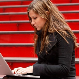 a woman sitting on a bench looking at a laptop