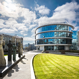 Exterior of a Northumbria University campus building with sculptures and lawn