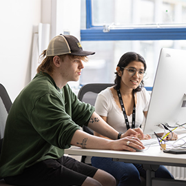 Two students working together at a computer in a university study space