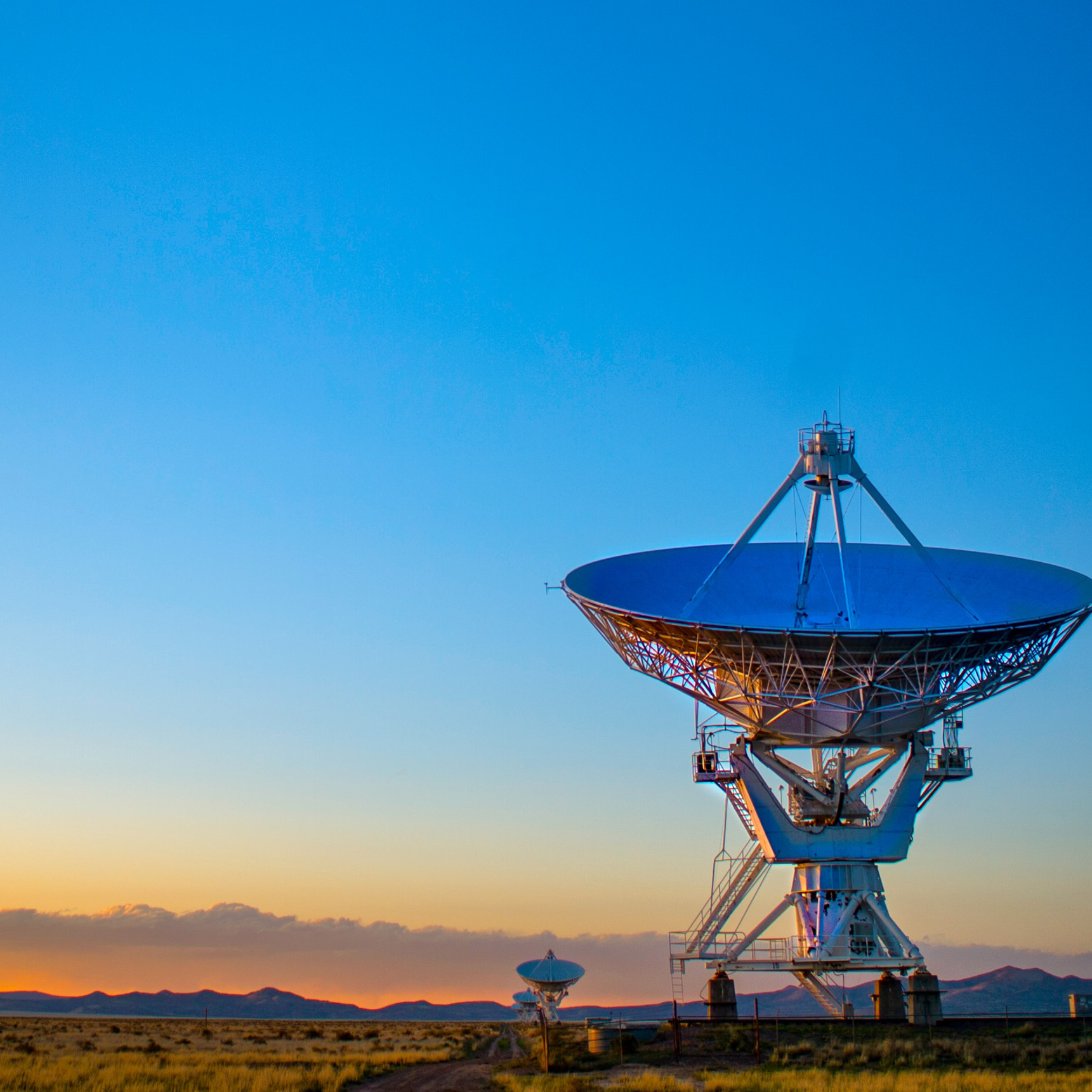 a radio telescope in a desert landscape at dusk