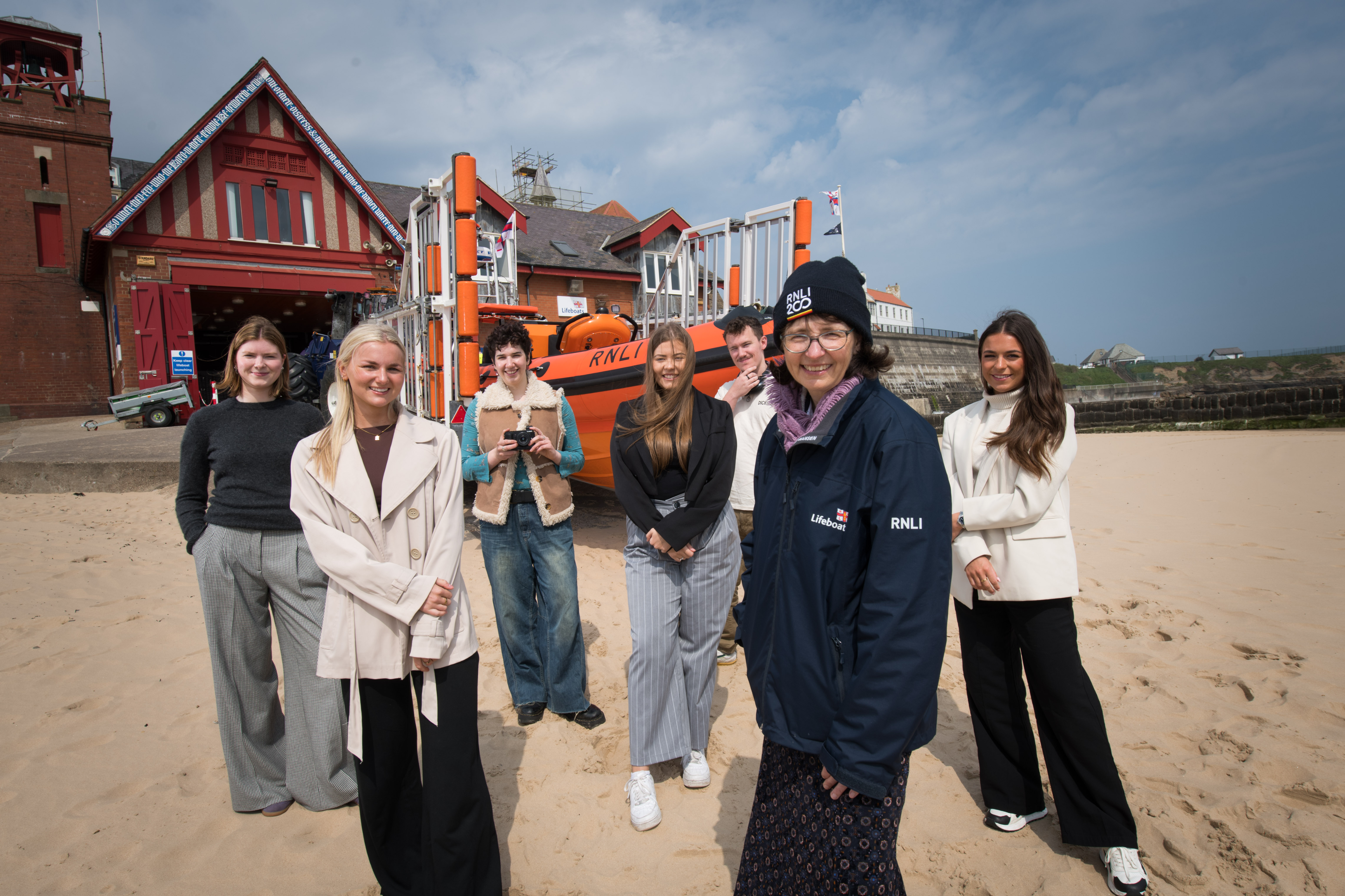 Group of people on the beach smiling at the camera