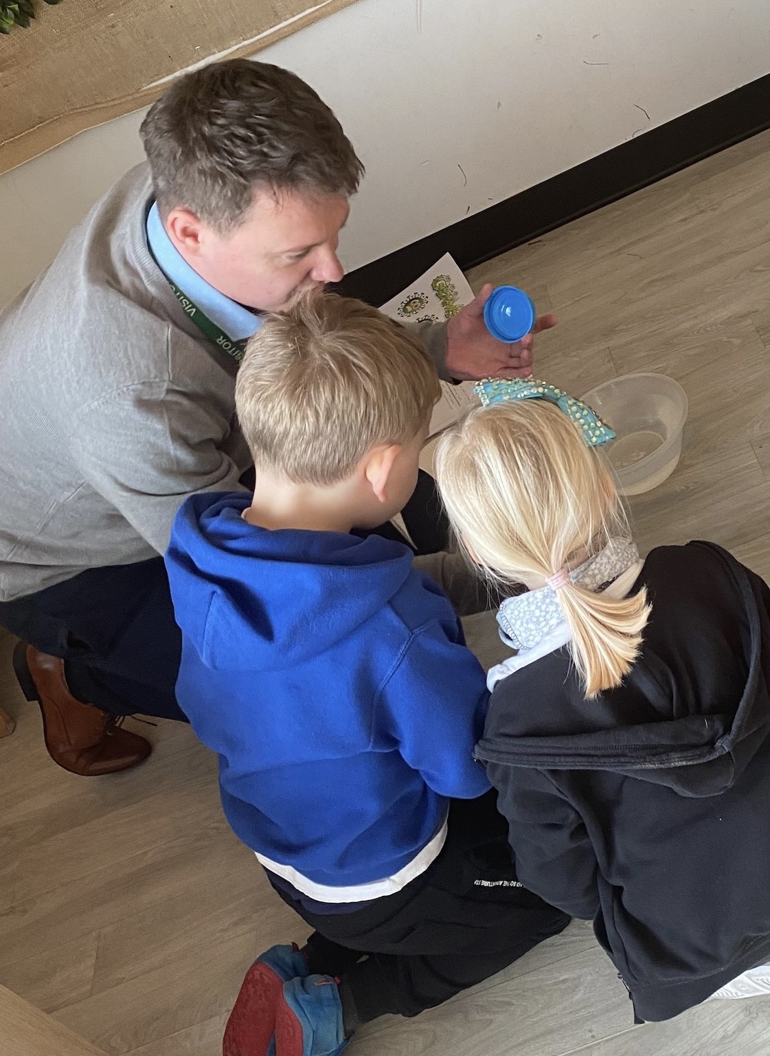 Primary Education teacher showing something to a girl and a boy
