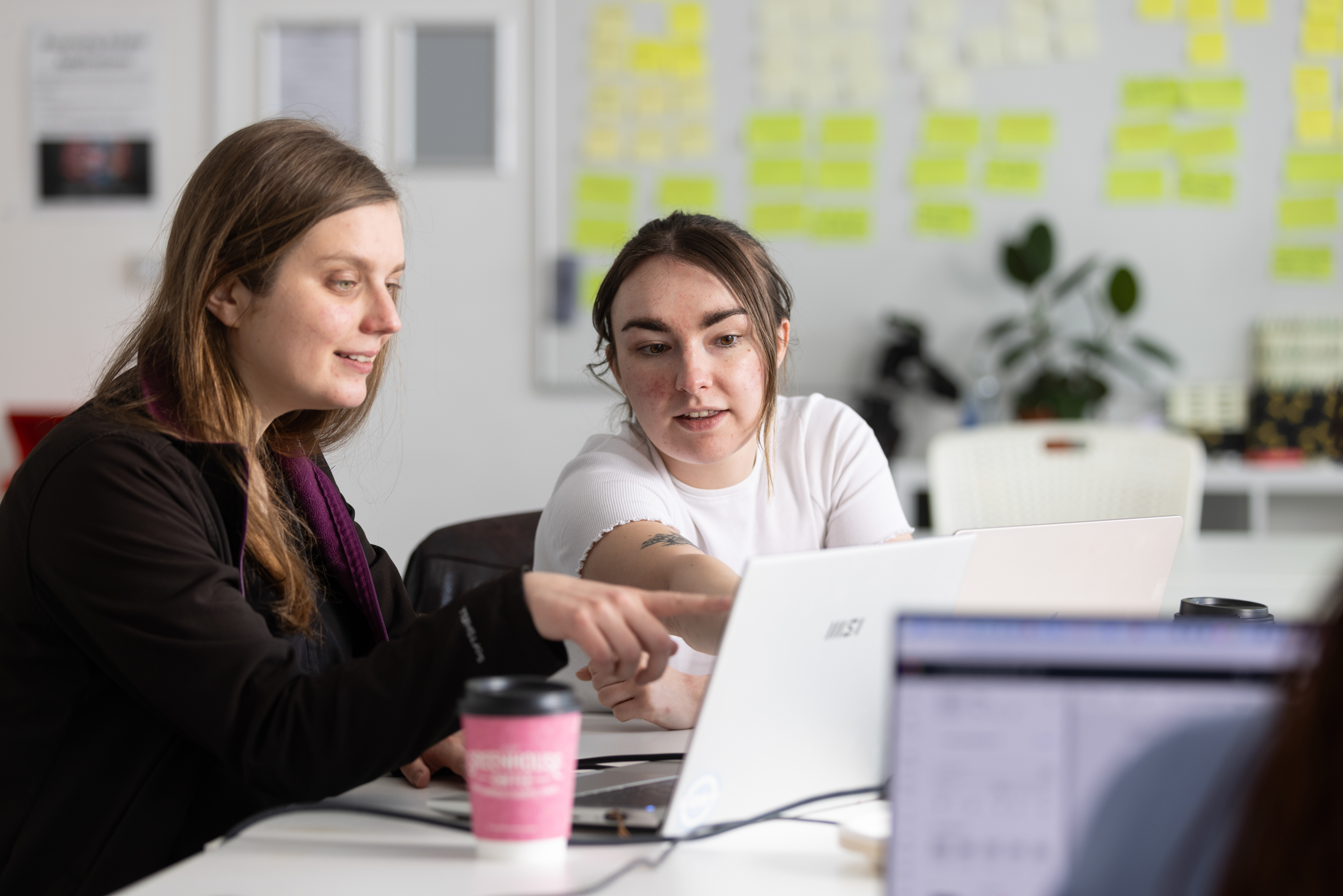 Female student and female teacher looking together at their laptop's screen