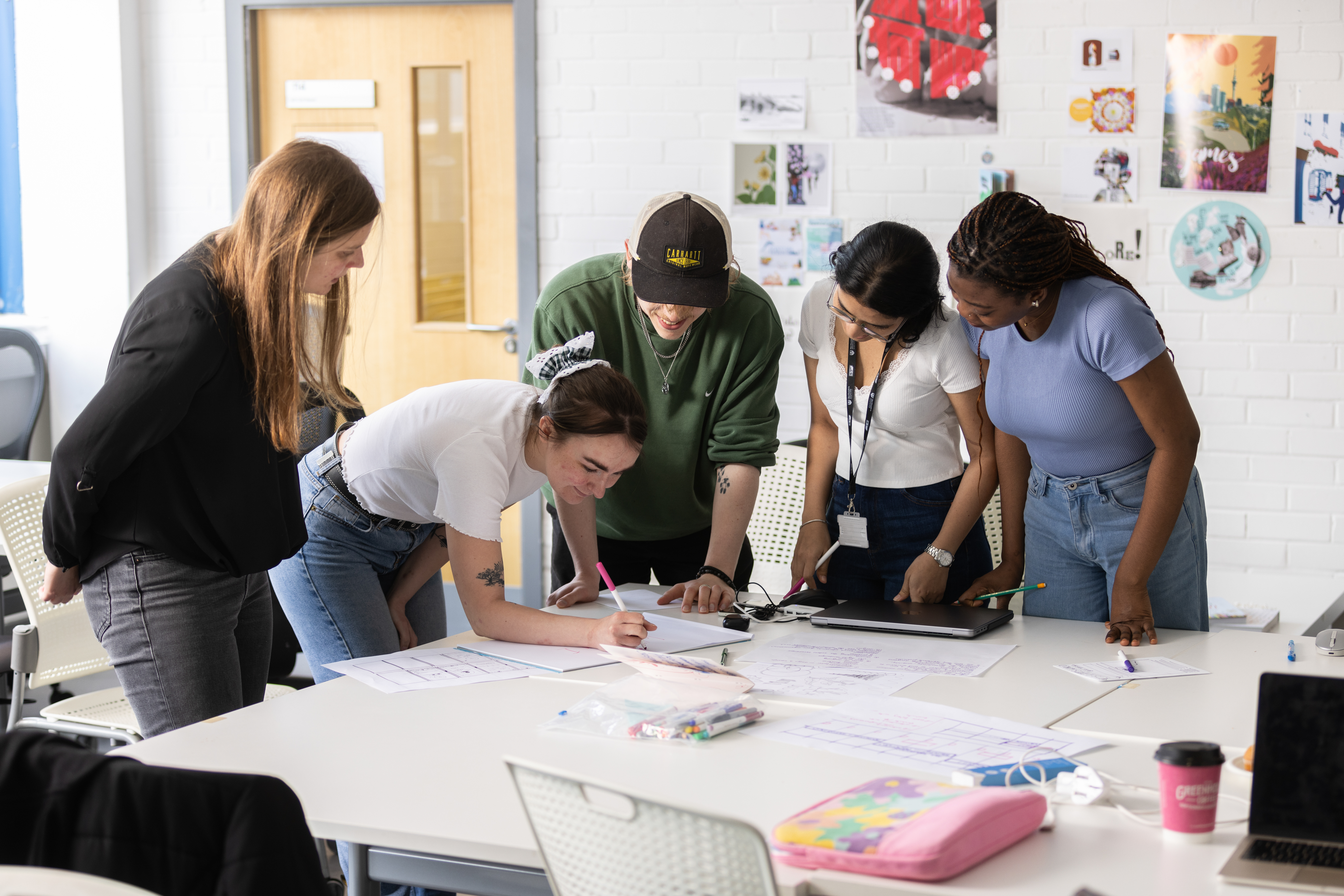 group of students working together at a desk, with one of them writing notes