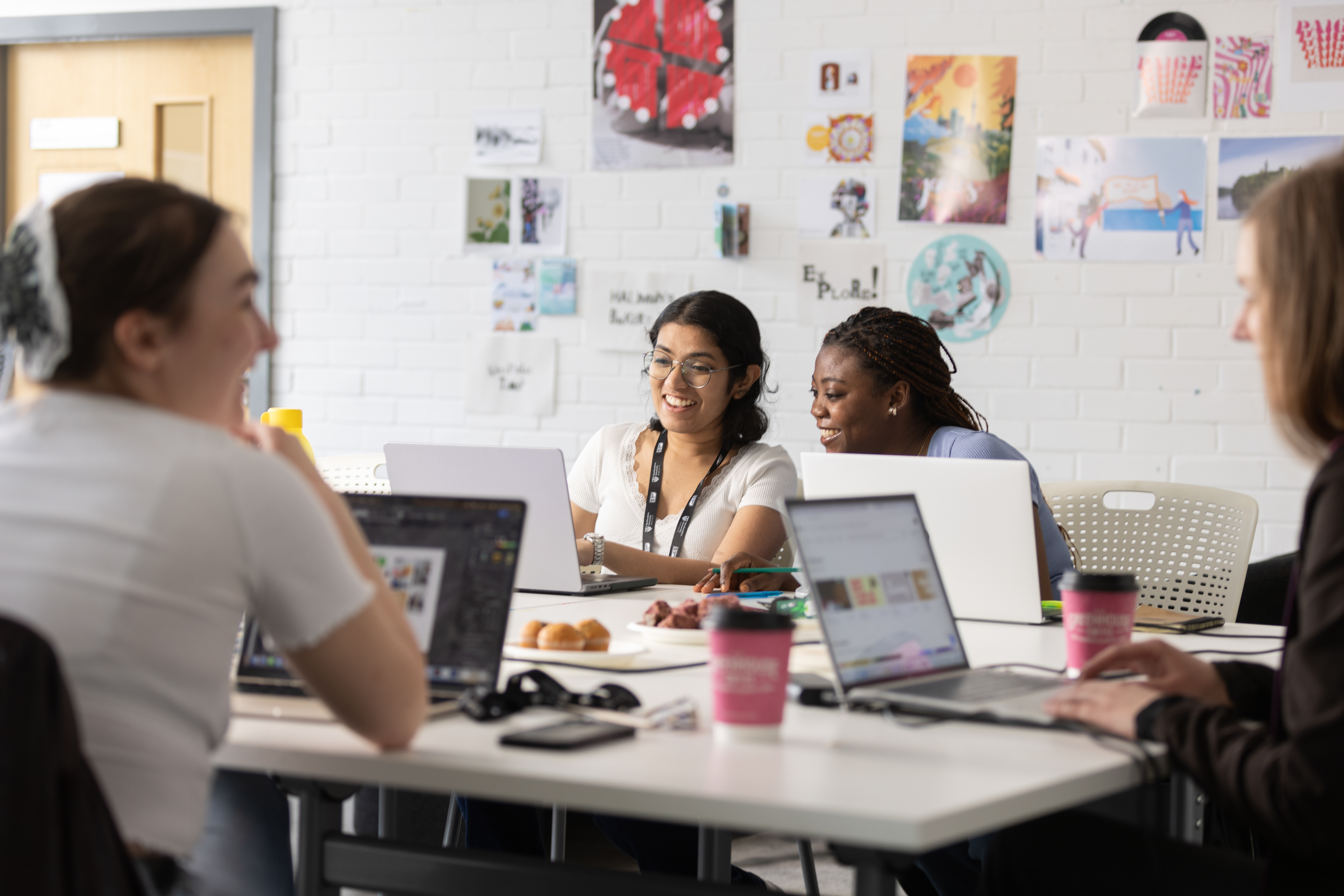 Image of 4 students working together at a table with their laptops in front of them