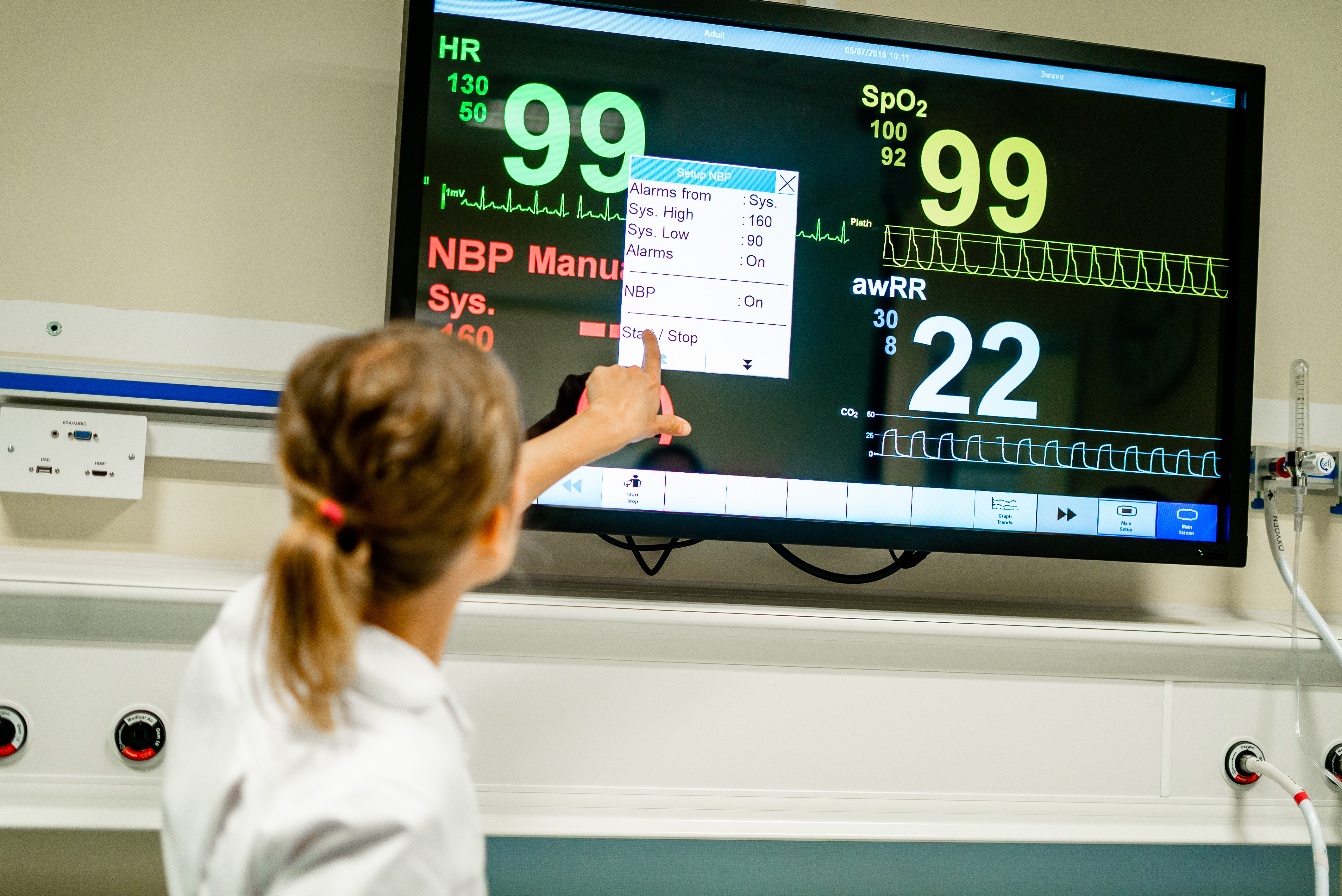Female nursing student wearing a nurse's uniform pointing at a screen