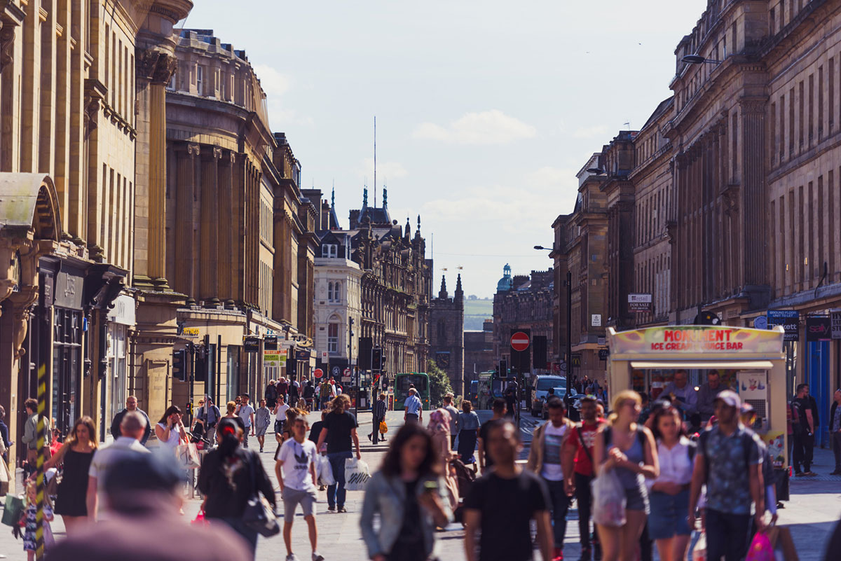 An image of Grainger Street in Newcastle, UK showing crowds of people on a sunny day
