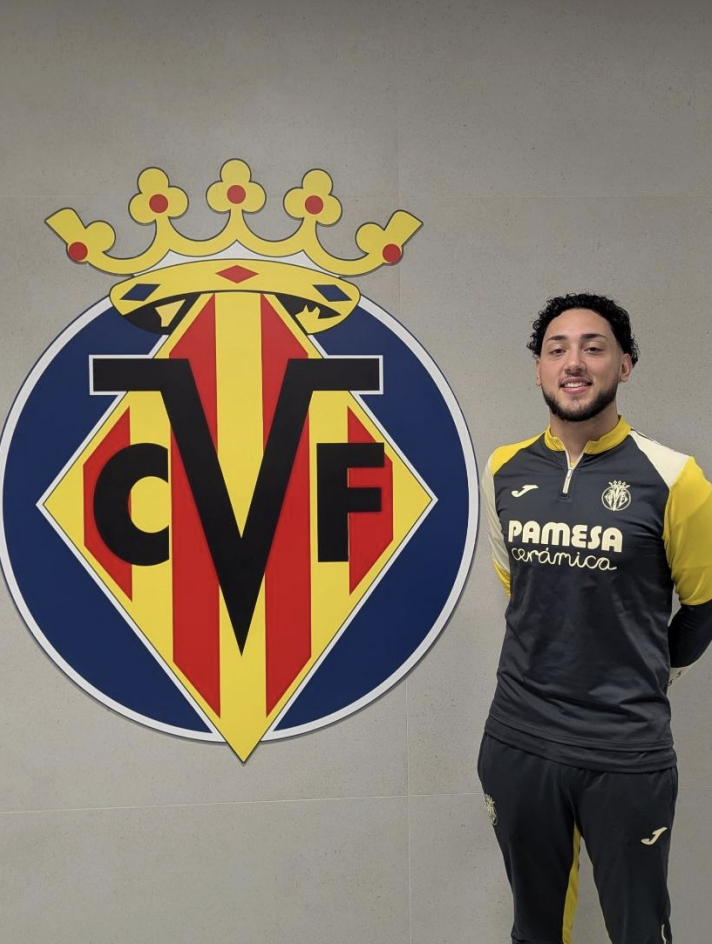 A young man standing in front of a football club logo. 