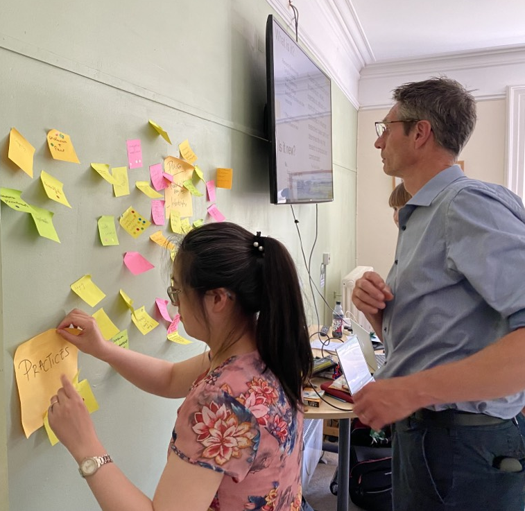 Two people looking at post it notes on board.