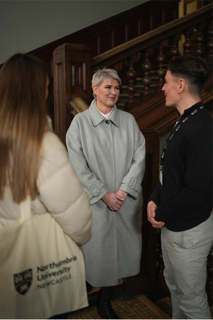 older woman talking to younger students