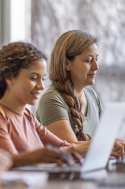 Two mature students using laptops