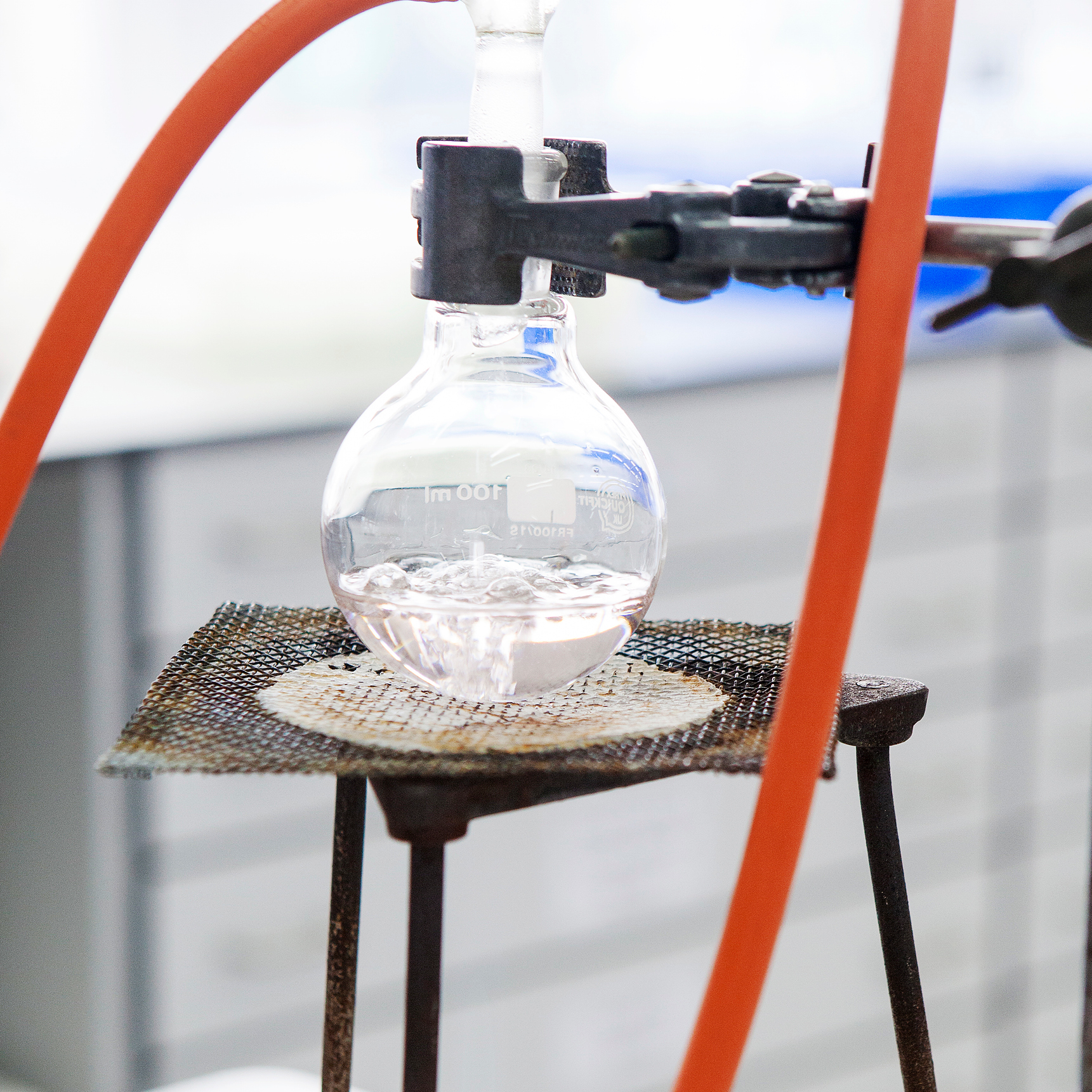 a round bottom flask held by a clamp over a bunsen burner