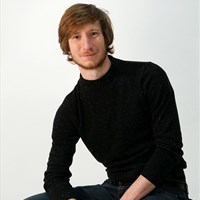 Academic smiling at camera, wearing black jumper