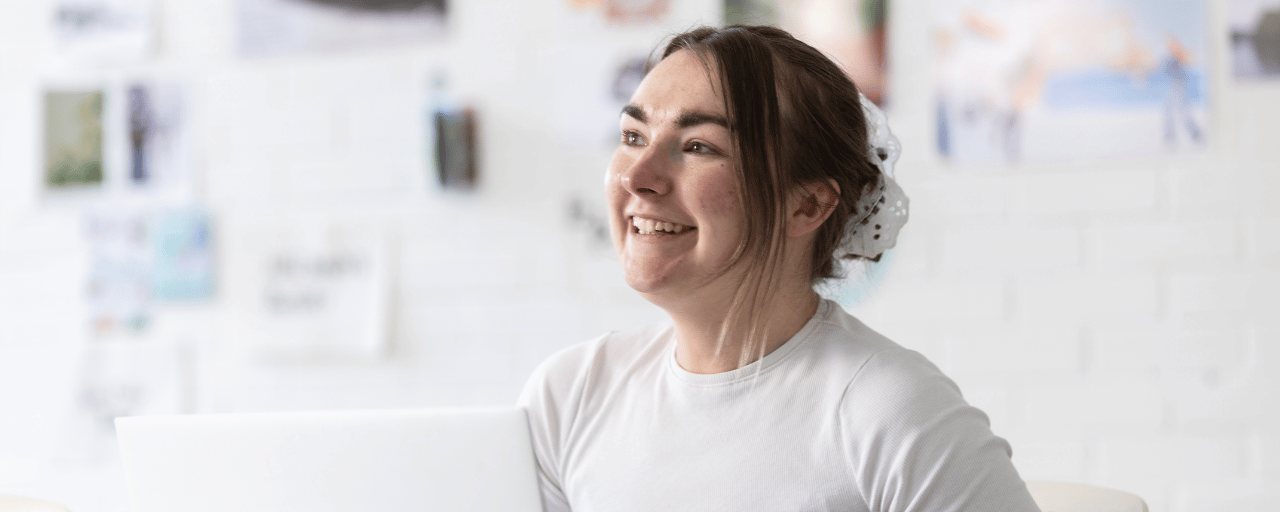 student smiling whilst working on a laptop