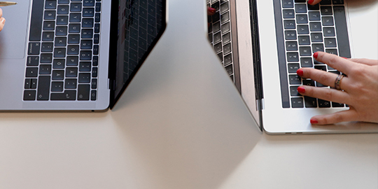 Top-down shot of two students using laptops.