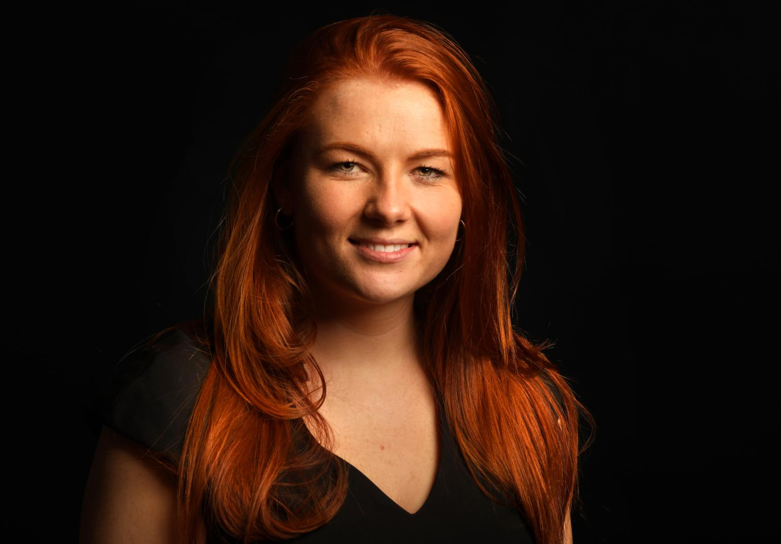 Profile image of Pippa Heron, graduate MSc Real Estate, wearing black top with red hair