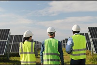 Stock engineers in safety vests on solar farm renewable energy
