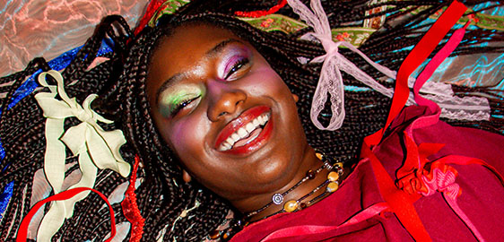 Smiling black female surrounded by colourful ribbons 