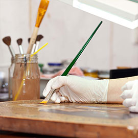 A gloved hand using a paintbrush