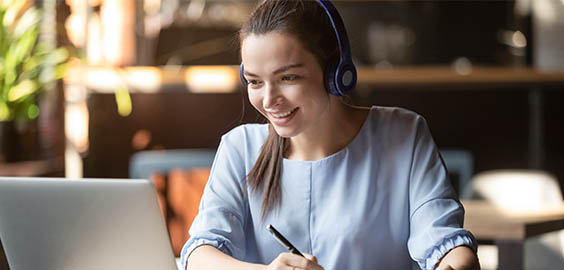 Smiling woman with headset on sat at a computer