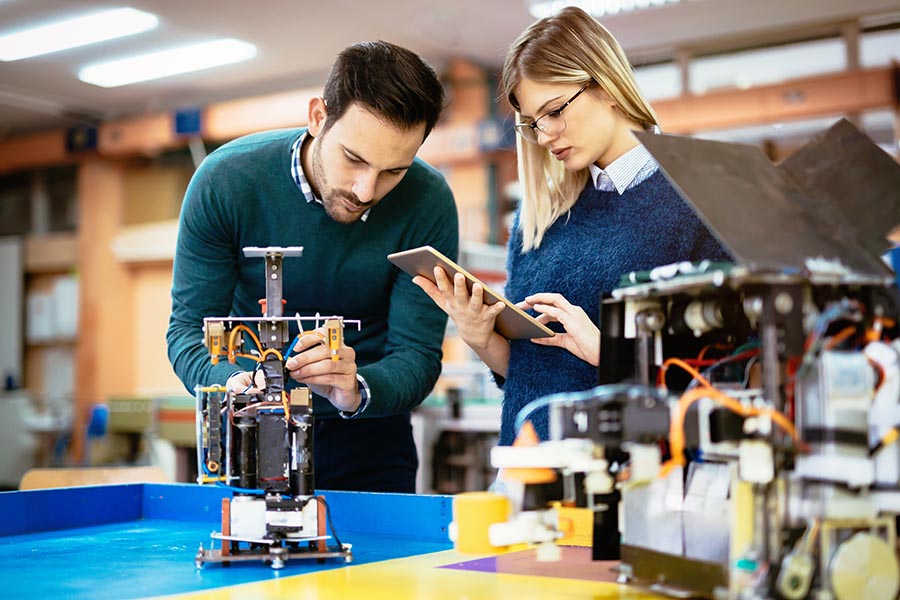 man and woman looking at model robot