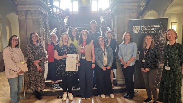 Photograph of members of the Gender Equality Steering Group who were involved in the Athena Swan Silver submission, with Rachel Brown, Director of EDI, holding the award certificate.
