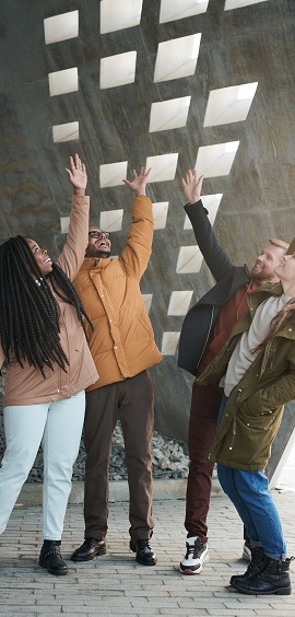 Four people standing next to each other and raising their hands in the air