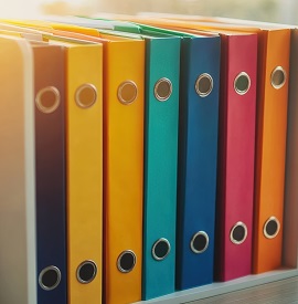 A bank of thick folders alongside one another, all in different colours 