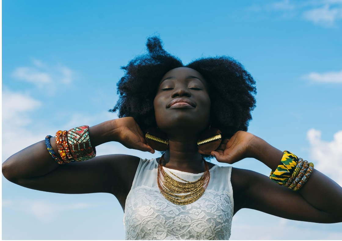 Women with eyes closed facing up to a blue sky