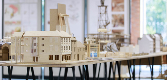 Tables across a room with models of buildings made by students on them.