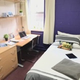 a bedroom with a bed and desk in a room