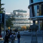 Northumbria University City Campus with CIS building on the right, behind some stone statues of people. The CCE building can be seen in the background.