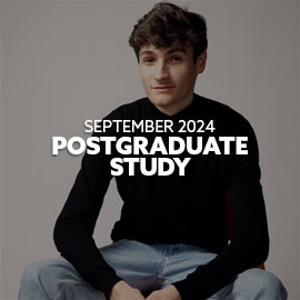 Close-up of a male, French student wearing a black long sleeved top - he is sitting on a chair and looking directly at the camera smiling. Text is embedded on the image reading: "September 2024 Postgraduate Study"