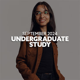 Female Indian student wearing a black top and brown jacket. She has her hands in her pockets, is wearing glasses and is smiling. Text is embedded on the image reading: "September 2024 Undergraduate Study"