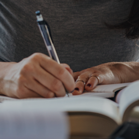 Close-up of someone making notes with a pen in a book.