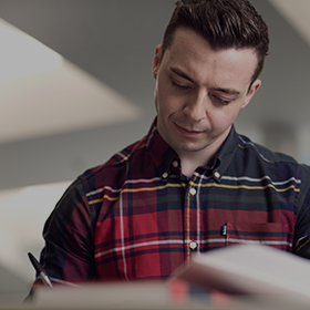 Close-up of a student in a red checkered shirt, studying in the Business Building.