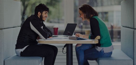 Image: Student receiving support from a member of staff in Student Central. They are both sitting facing each other within one of the beach hut style sitting areas.