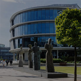 Image of the Northumbria Computer and Information Sciences Building and the statues on the surrounding grounds.