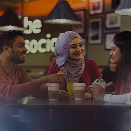 Three students talking around a table