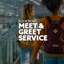 Two individuals wearing backpacks, carrying suitcases through the airport. There is text embedded on the image that reads: "Book now: Meet & Greet Service"