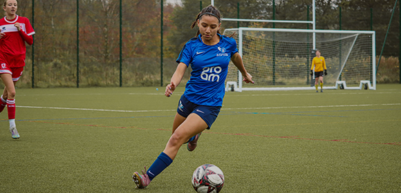 i2i female-athlete kicking a soccer ball.