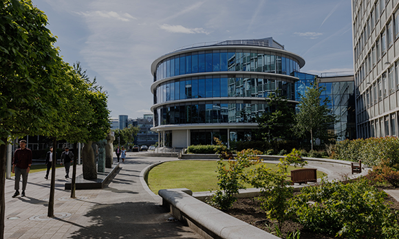 Wide-shot of the CIS building on Newcastle City Campus. It is a sunny day and students are walking past the frame.