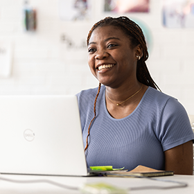 Student smiling, working on a laptop.