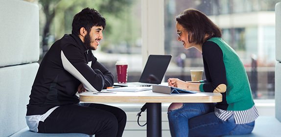 A student and a member of staff sat in a booth, discussing a topic in Student Central.