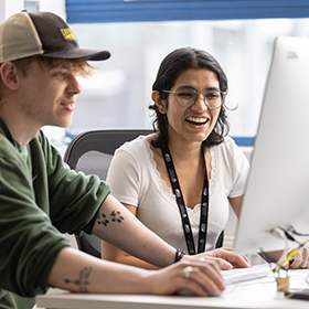 Two Design students working on an Apple Mac together.