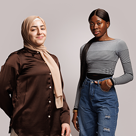 Two students stood smiling and looking directly at the camera, as part of the I Am Northumbria campaign.