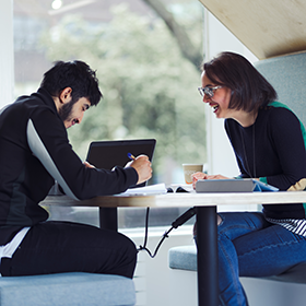 A student and a support member of staff sat together in a booth in Student Central.