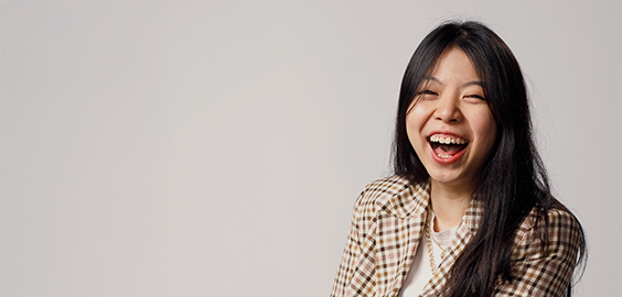 Student of South East Asian decent laughing, looking directly at the camera as part of the 'I Am Northumbria' photoshoot campaign.