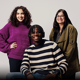 Three students stood together, smiling, as part of the 'I Am Northumbria' photoshoot.