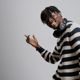 Image of a male student dancing with headphones around his neck, against a white background as part of the 'I Am Northumbria' campaign.